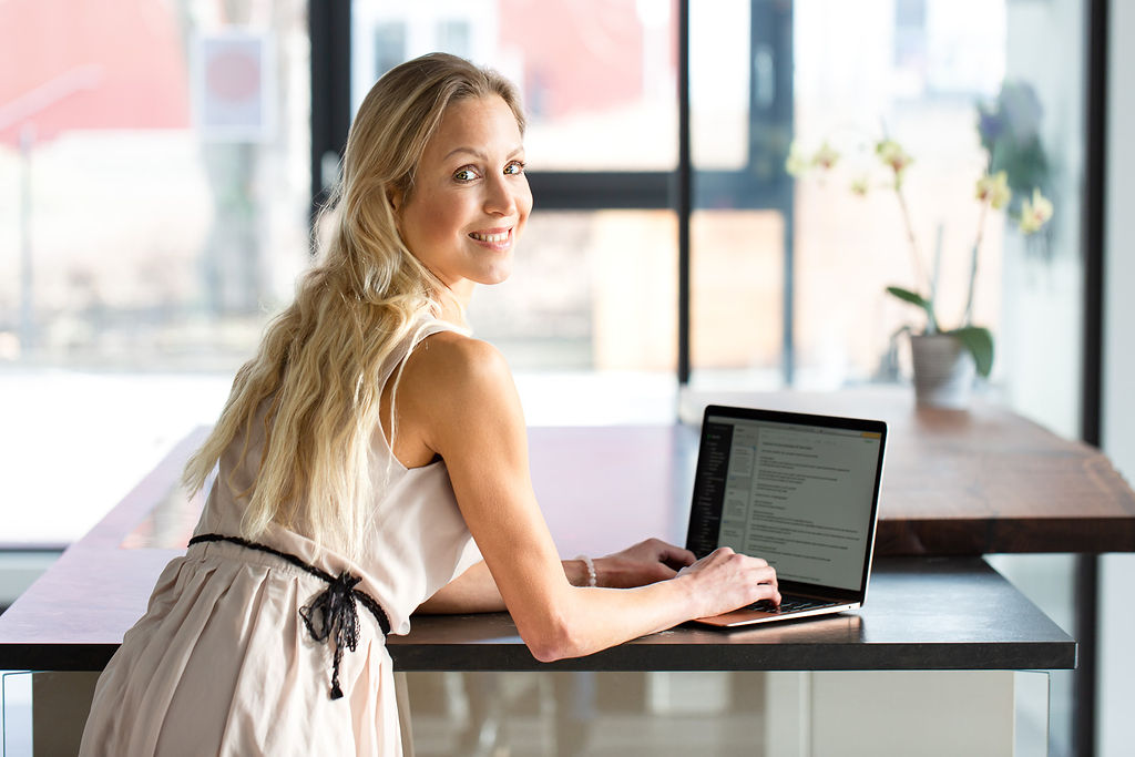 Anne Jansson lächelt an ihrem Arbeitsplatz am Laptop.